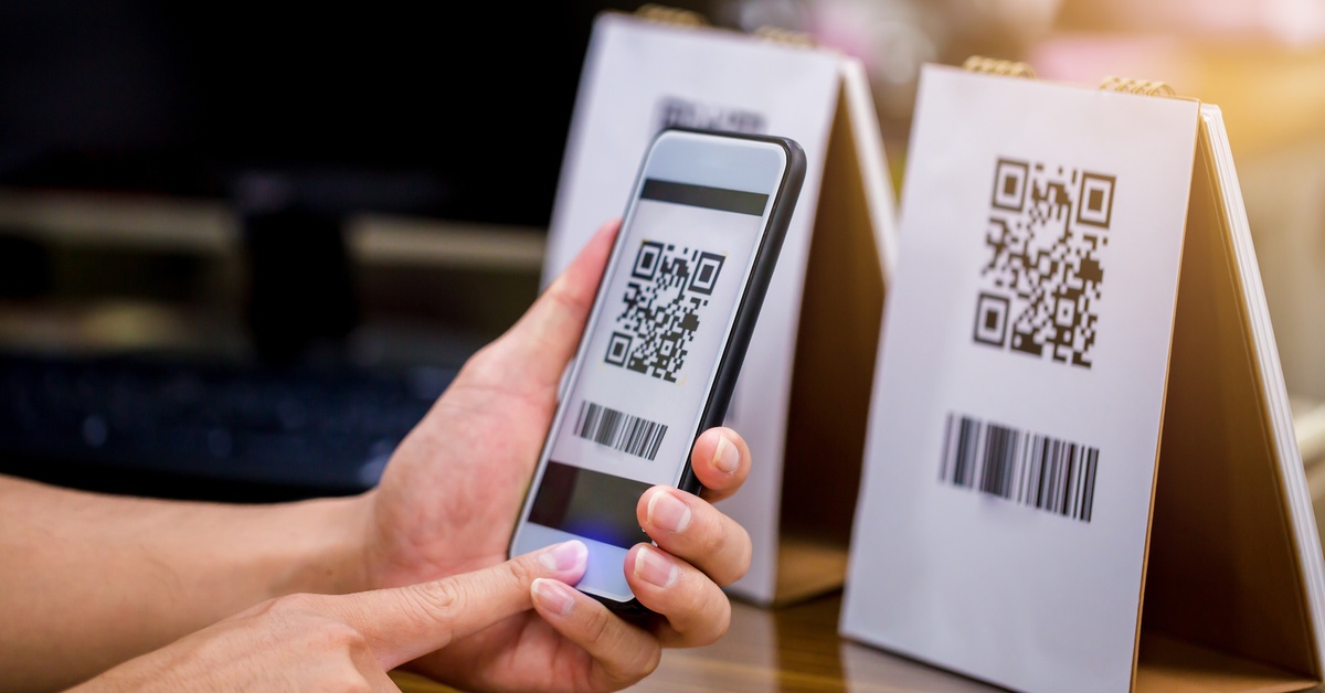 A customer holds their phone as they take a photo of the QR code listed on a piece of paper. The paper is on a table tent.